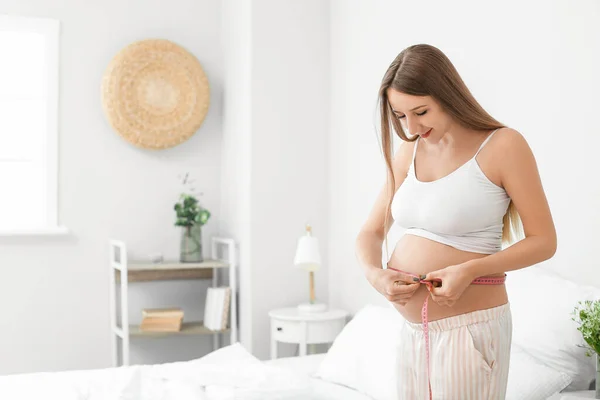 Молодая Беременная Женщина Измеряет Свой Живот Спальне — стоковое фото