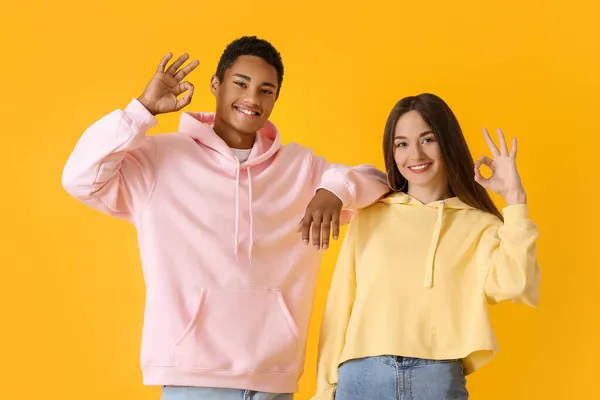 Elegante Jovem Casal Capuzes Mostrando Fundo Amarelo — Fotografia de Stock