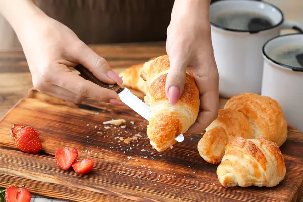 Vrouw Snijden Smakelijke Croissant Aan Tafel — Stockfoto