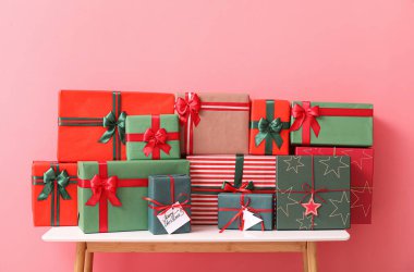 Renk arkaplanında farklı Noel hediyeleri olan masa