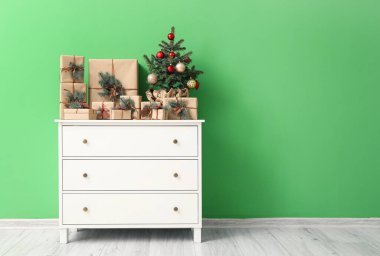 İçinde Noel ağacı olan çekmeceler ve renkli duvarın yanında hediyeler.