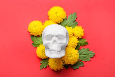 Meksika Ölüler Günü için insan kafatası (El Dia de Muertos) ve kırmızı arka planda çiçekler