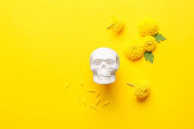 Meksika Ölüler Günü için insan kafatası (El Dia de Muertos) ve sarı arka planda çiçekler