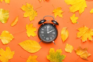 Alarm saati ve sonbahar yaprakları renk arkaplanda. Gün ışığı kaydetme süresi bitti