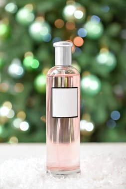 Parfüm şişesi ve Noel topları bulanık arka planda.