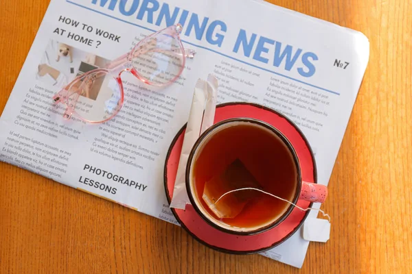 Tahta Arka Planda Bir Fincan Sıcak Çay Gazete Gözlük — Stok fotoğraf