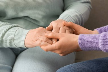 Evde büyükannenin elini tutan genç bir kadın.