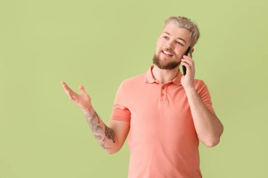 Genç adam renkli arka planda modern cep telefonuyla konuşuyor.