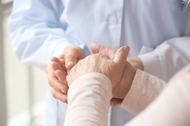 Klinikteki doktor ve yaşlı kadının elleri, yakın plan.