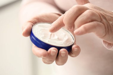 Evdeki ellerine makyaj kremi süren yaşlı bir kadın, yakın plan.