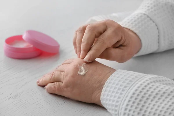 Mujer Mayor Aplicando Crema Cosmética Sus Manos Mesa — Foto de Stock