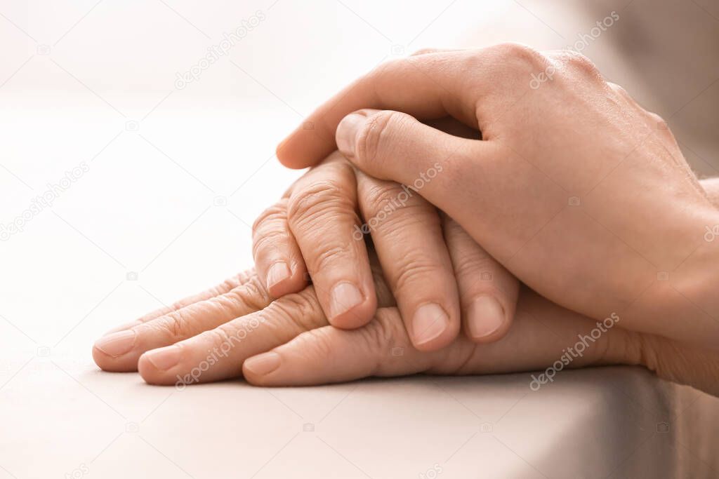 Young woman holding hands of grandmother at table