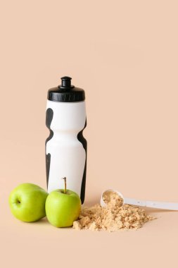 Protein karışımlı şişe, toz ve elmalarla ölçme kepçesi renk arkaplanda