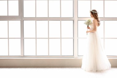 Pencerenin yanında bir buket çiçekli güzel gelin