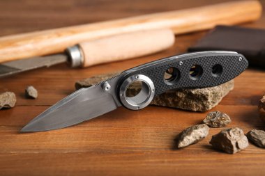 Kauçuk saplı katlanmış çakı ahşap masanın üzerinde.