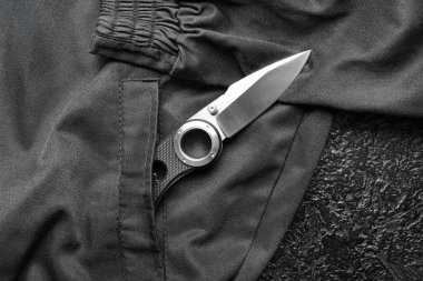 Siyah takım elbise arka planında plastik saplı katlanmış çakı.