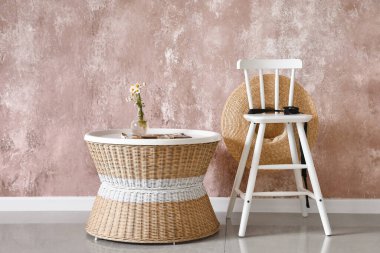 Modern sandalye ve hasır masa renk duvarının yanında.