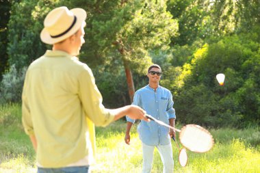Dışarıda badminton oynayan genç adamlar.