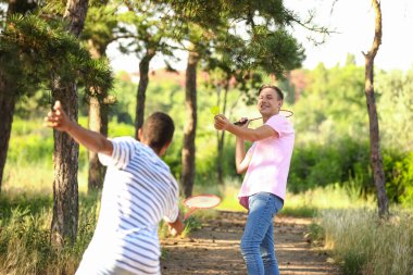 Dışarıda badminton oynayan genç adamlar.