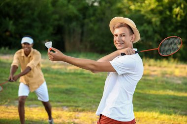 Dışarıda badminton oynayan genç adamlar.