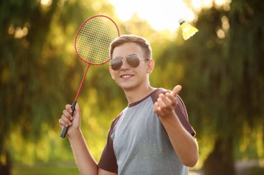 Genç adam dışarıda badminton oynuyor.