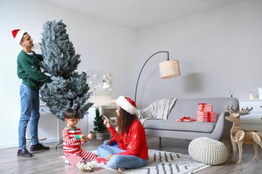 Evde Noel ağacı süsleyen çocuklu mutlu bir aile.