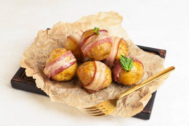 Beyaz arka planda domuz pastırması ve lezzetli fırında patateslerden oluşan ahşap tahta.