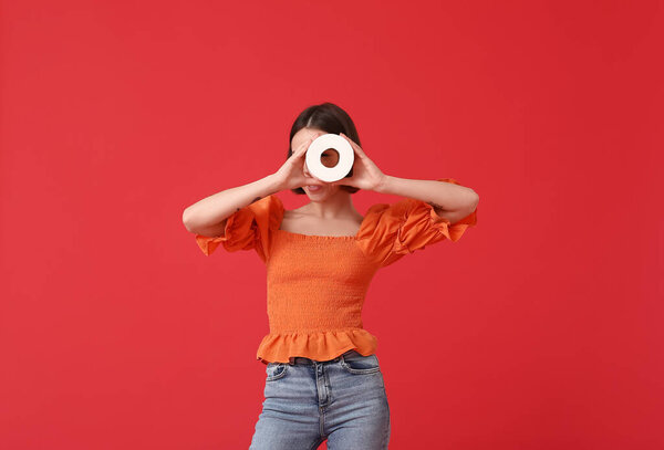 Young woman with toilet paper on color background