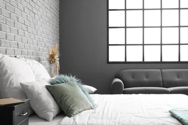グレーレンガの壁の近くに緑の枕付きの大きな快適なベッド — ストック写真