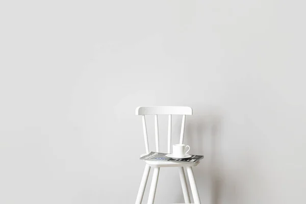 光の壁の近くのコーヒーと雑誌のカップと椅子 — ストック写真