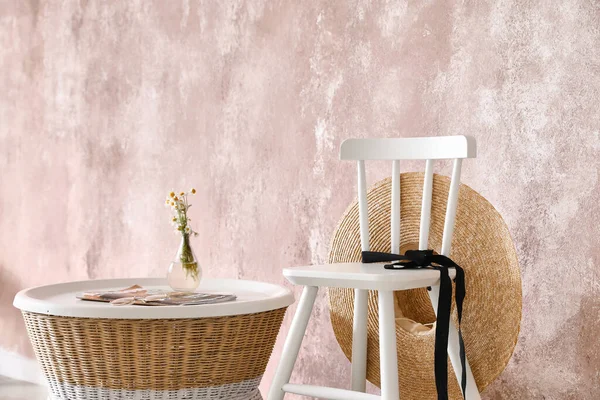 Modern sandalye ve hasır masa renk duvarının yanında.