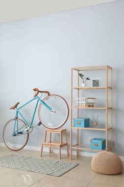 Merdivenli bisiklet, raf ünitesi ve ışık duvarının yanında puf.