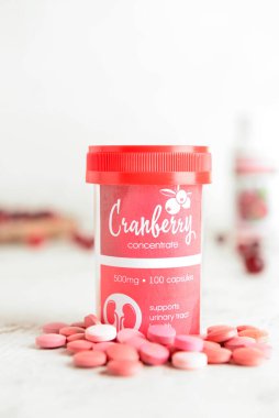 Hafif arka planda sağlıklı yabanmersini haplarıyla dolu bir şişe.