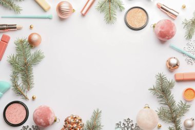 Beyaz arkaplanda köknar dalları ve makyaj kozmetiğinden yapılmış çerçeve