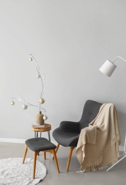 Koltuk ve masa. Gri duvarın yanında Noel süsü var.