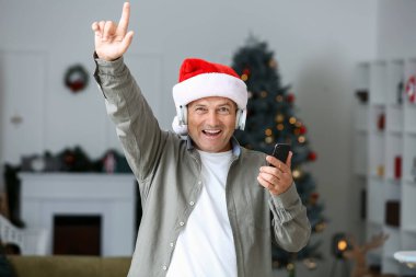 Evde Noel müziği dinleyen olgun bir adam.