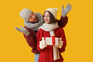 Genç bir kadın, erkek arkadaşından Noel hediyesi alıyor. Renkli arka plan.