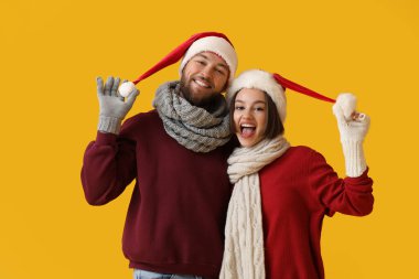 Şık kış kıyafetleri ve renkli Noel Baba şapkaları giyen mutlu genç çift.