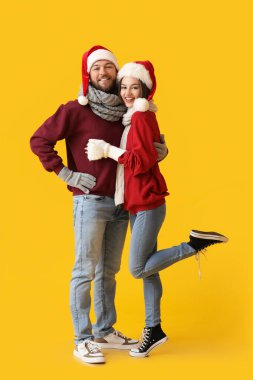 Şık kış kıyafetleri ve renkli Noel Baba şapkaları giyen mutlu genç çift.