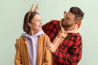 Şık kış kıyafetleri içinde mutlu genç bir çift ve açık arkaplanda Noel süsüsüyle