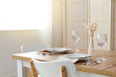 Bulaşık ve vazoyla aydınlık odada yemek masası