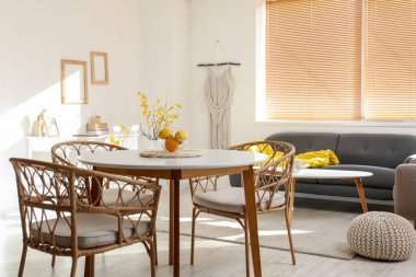 Portakallı yemek masası ve ışıklı odada hasır sandalyeler