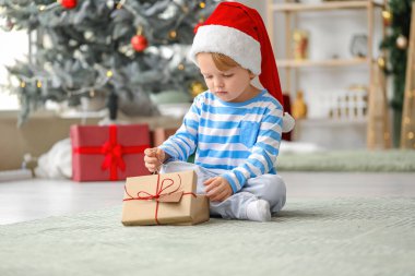 Noel Baba şapkalı küçük çocuk ve Noel arifesinde evde hediyesiyle