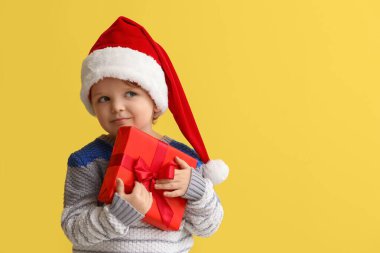 Noel Baba şapkalı komik küçük çocuk ve renkli bir Noel hediyesi.