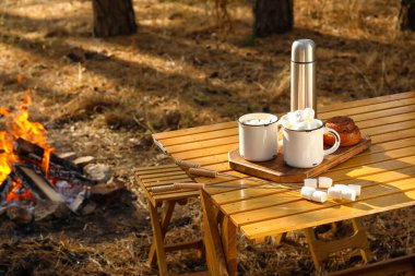 Sonbahar ormanında lezzetli şekerlemeler ve çöreklerle dolu bir fincan sıcak çikolata.