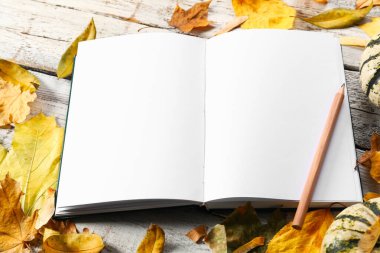 Güzel sonbahar kompozisyonu, kitap ve yapraklar beyaz ahşap arka planda.