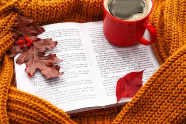 Güzel bir sonbahar kompozisyonu, kitap, bir fincan kahve ve sıcak süveter yaprakları.