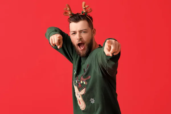 若いです男でスタイリッシュなクリスマス服ポインティングでビューア上の色の背景 — ストック写真