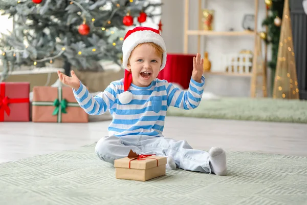 サンタの帽子の小さな男の子とクリスマスの前夜に家での贈り物 — ストック写真