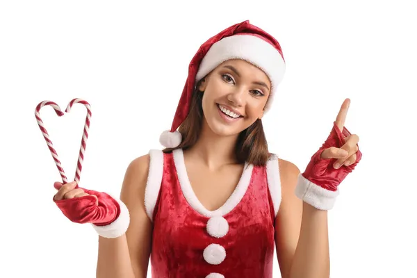 身穿圣诞老人服装 头戴糖果手杖的漂亮女人指着白色背景的东西 — 图库照片